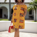 Woman in a yellow patterned dress with red accessories standing outdoors.