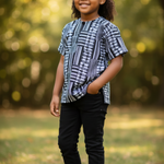 Child wearing a Black White Kente Ankara Dashiki shirt and black cap outdoors