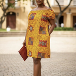 Woman wearing a yellow patterned dress standing outdoors on a paved area.