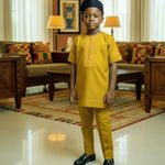 Child in yellow Dupsie's traditional Dashiki Shirt standing in a living room with decor.