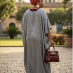 African clothing for women featuring Rafiat, a silver silk-like African dress with intricate red embroidery highlighting luxury African fashion.
