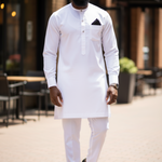 All-white slim-fit African Senator dashiki by Dupsie’s with vertical pocket embroidery, 3-button neckline, French cuffs, and matching drawstring pants.