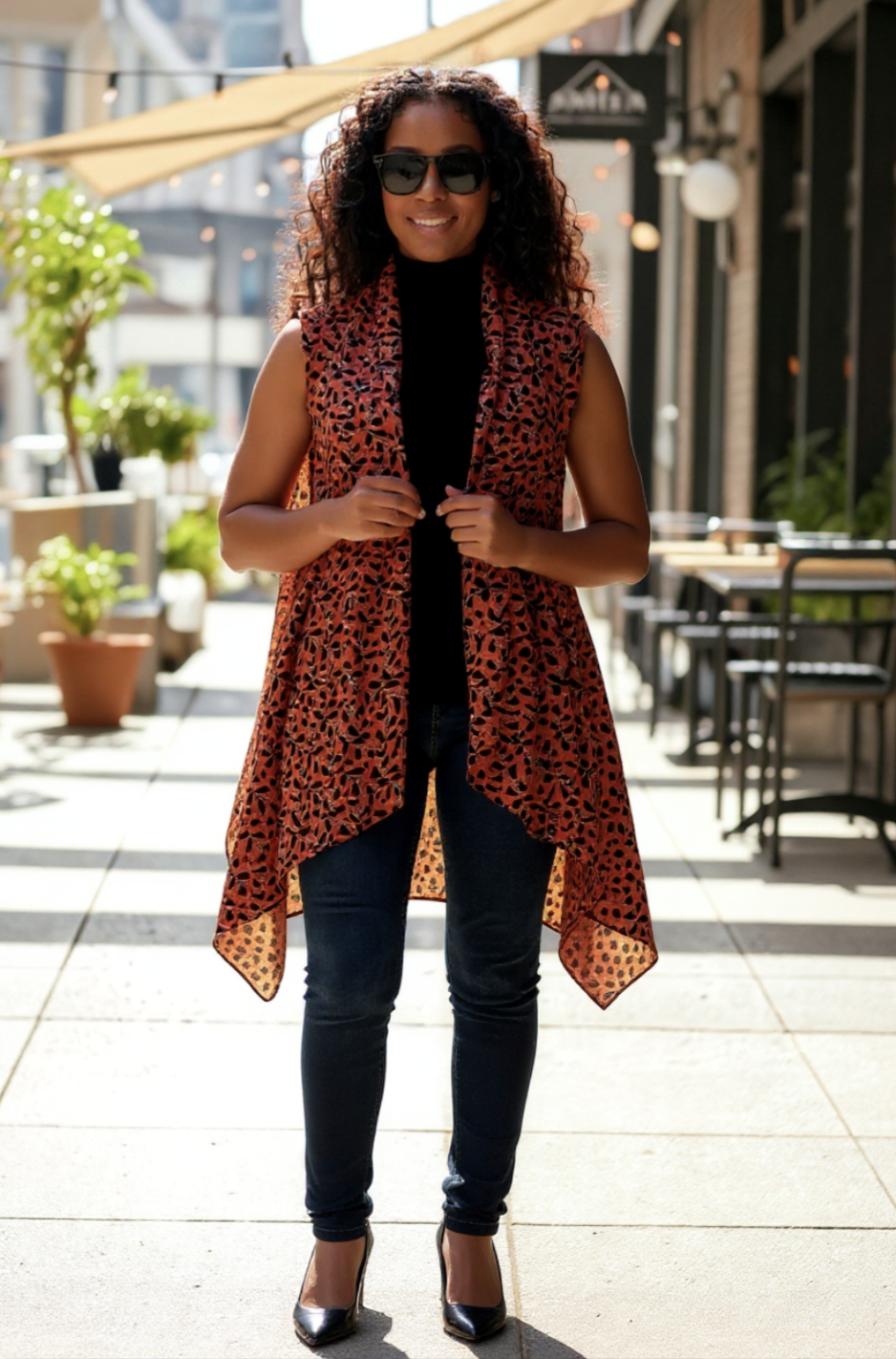 Close-up of lightweight leaf print fabric on burnt-orange African vest shawl; rolled-edge finish