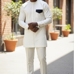 Man wearing a white traditional outfit with a black pocket square in an urban setting.