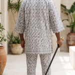 African wedding Agbada for groom in elegant white embroidered lace with grey accents.