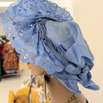 Closeup of fan crown showing rhinestones, glitter, and decorative cutout holes on green Aso Oke.